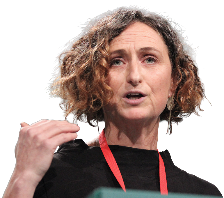 Person with curly hair wearing a black shirt and red lanyard, gesturing while speaking against a black background.